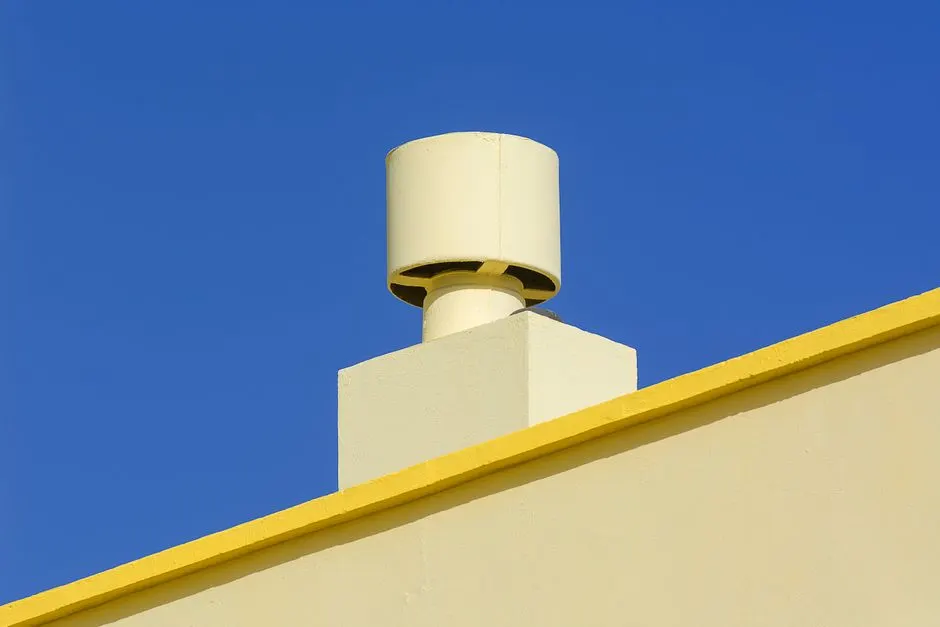 Yellow industrial chimney against a vibrant blue sky, representing modern architecture.